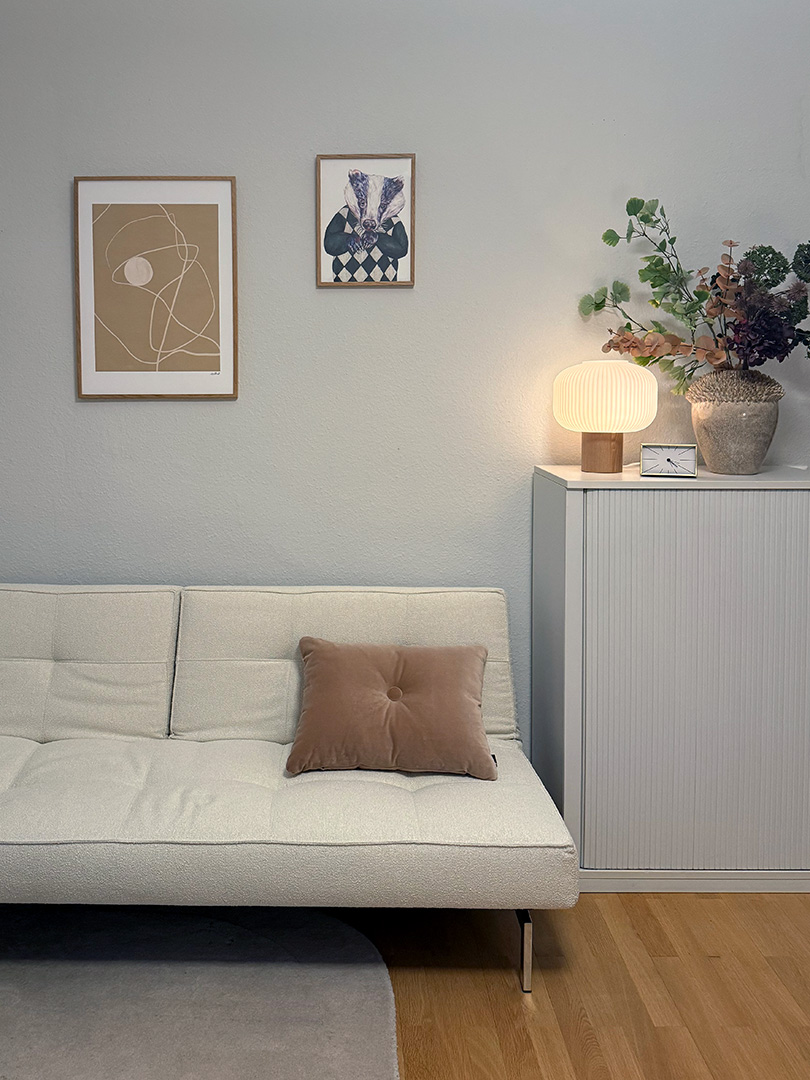 Praxisraum der Privatpraxis für Psychotherapie, mit Sofa, Bildern, Blumen und Lampe.