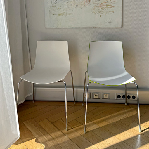 Wartebereich der Privatpraxis für Psychotherapie: ein Raum mit zwei Stühlen, Parkettboden und Kunst an der Wand. Durch einen leichten Vorhang fällt Sonnenlicht in das Zimmer.