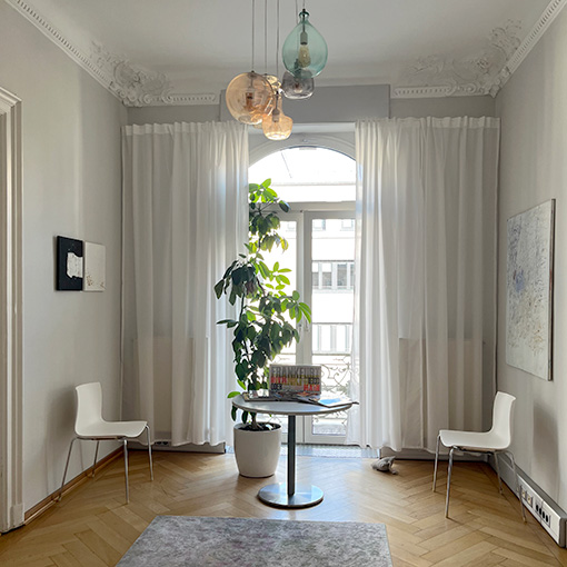 Wartebereich der Privatpraxis für Psychotherapie: ein ansprechender Raum mit zwei Stühlen, einem Tisch, Kunst an den Wänden und einer Zimmerpflanze.